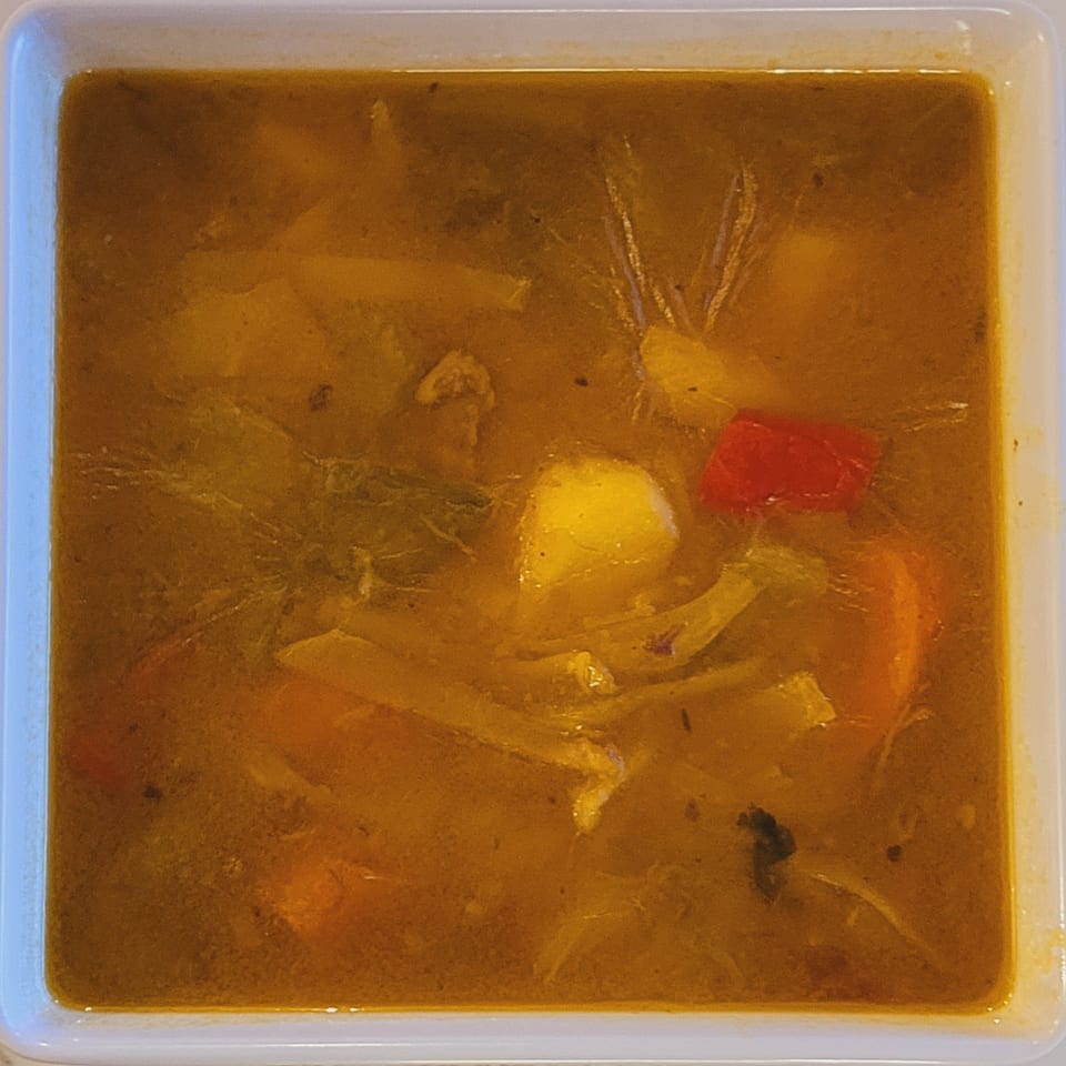 A close-up of Haitian soup from Vingoute Restaurant, with vegetables and a rich broth.